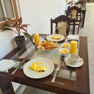 a wooden table with plates of food and orange juice at Ovenro Safari Hotel & Restaurant Yala, Kataragama in Kataragama