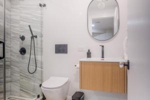 a bathroom with a toilet and a sink and a mirror at Charming Garden Lvl Brownstone in Brooklyn