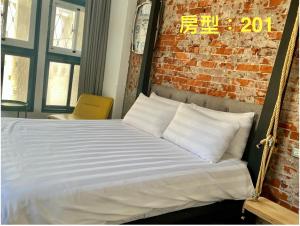 a bed with white pillows in front of a brick wall at 阡陌-分享民宿 in Tainan