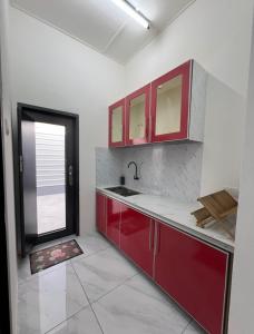 an empty kitchen with red cabinets and a window at Intan Pearl in Teluk Intan
