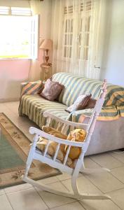 ein Wohnzimmer mit einer Couch und einem weißen Schaukelstuhl in der Unterkunft Paradis Créole à Bellevue Sainte-Rose in Sainte-Rose + 8 Fotos