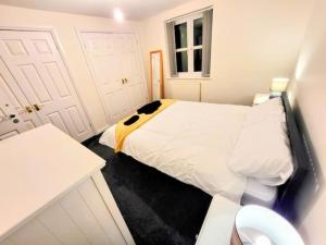 a small white bedroom with a bed and a window at Large Modern House with Private Parking in Heeley