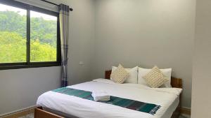 a bedroom with a white bed with a window at Houngvilai Guesthouse in Ban Sôphoun