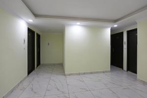 a hallway with white walls and a tile floor at Hotel O Lime Wood in Dehradun