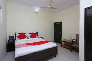 a bedroom with a bed with red pillows at Hotel O Lime Wood in Dehradun +26 photos