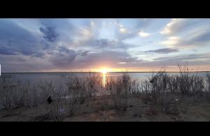 a sunset on a beach with the sun in the water at Kiowa RV Park in Eads