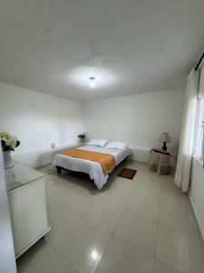 a bedroom with a bed with an orange blanket on it at Manaju - Finca Campestre y Glamping in Ibagué +5 photos
