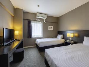a hotel room with two beds and a flat screen tv at KOKO HOTEL Yokohama Tsurumi in Yokohama +65 photos