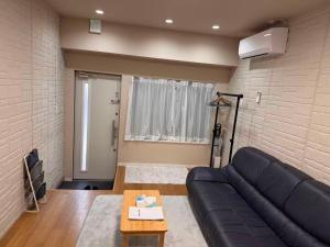 a living room with a black couch and a brick wall at Cozy House Namba in Osaka