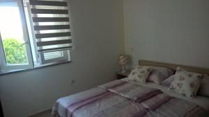 a white bedroom with a bed with a window at Villa Palas Apartments 2 in Rogoznica