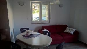 a living room with a red couch and a table at Villa Palas Apartments 2 in Rogoznica