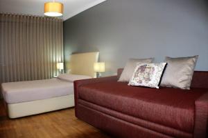 a bedroom with a bed and a couch with a pillow at Studios Porto Solar in Porto