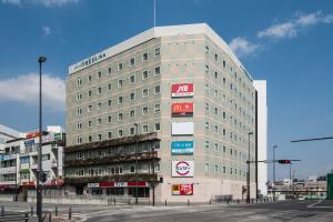 um grande edifício cinzento com placas na lateral em Sotetsu Fresa Inn Yokohama Totsuka em Yokohama