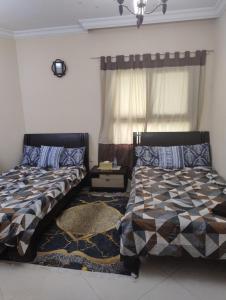 a bedroom with two beds and a window at Cityscape Retreat Apartment in Sharjah