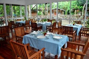 a dining room with tables and chairs and windows at Borneo Nature Lodge in Sukau