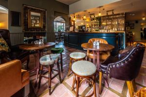 a restaurant with tables and chairs and a bar at Greyhound Hotel in Sutton