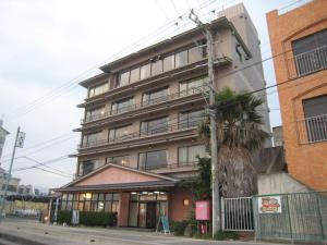an apartment building with a palm tree in front of it at Utsumionsen Ichizu in Minamichita