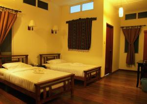2 camas en una habitación con paredes amarillas y suelo de madera en Borneo Nature Lodge, en Sukau