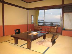 a living room with a wooden table and a chair at Utsumionsen Ichizu in Minamichita
