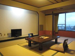 a living room with a table and a tv at Utsumionsen Ichizu in Minamichita