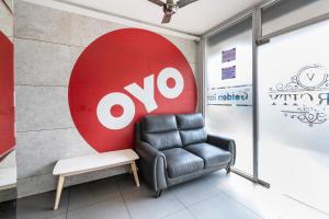 a chair in a room with a large ovo sign on a wall at Hotel O Platinum Inn in Bengaluru