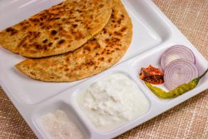 a lunch box with a pita bread and dip and onions at Hotel O Platinum Inn in Bengaluru