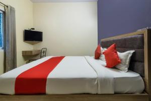 a bedroom with a red and white bed with pillows at Hotel O Platinum Inn in Bengaluru +30 photos