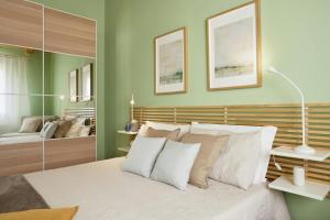 a bedroom with green walls and a bed with white pillows at Tropical Fruit Garden Villa In Lido Di Noto in Noto