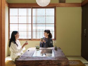 two women sitting at a table with drinks at Irori Cabin biei in Biei