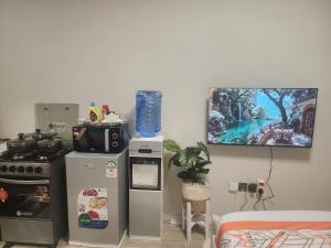 Il comprend une cuisine équipée d'un réfrigérateur et une télévision murale. dans l'établissement Farrey Homes Studio Near Jkia and Sgr, à Syokimau