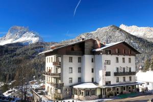 a large building with mountains in the background at Hotel Cima Belpra' in San Vito di Cadore