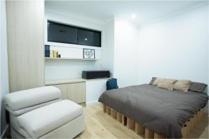 a bedroom with a bed and a chair and a tv at The Oak & Sand House 3BHK Cosy stay in Modbury +4 photos