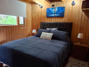 a large blue bed in a room with wooden walls at Cabañas by Puertecillo in Puertecillo