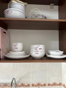 a shelf with plates and bowls and dishes on it at AzNiLux Boulevard in Muruntau