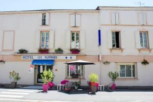 a hotel with chairs and an umbrella in front of a building at Hôtel les Platanes in Villeneuve-sur-Lot