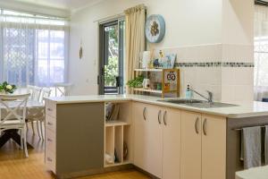 a kitchen with white cabinets and a sink at The Lazy Pelican in Tin Can Bay