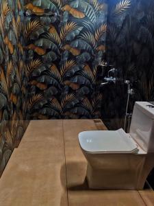 ein Badezimmer mit Toilette und Wandgemälde in der Unterkunft Periyaveettil Heritage in Neyyāttinkara