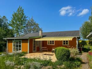 une petite maison orange avec un patio dans une cour dans l'établissement Holiday Home With Field Views & Fanefjord Charm, à Askeby