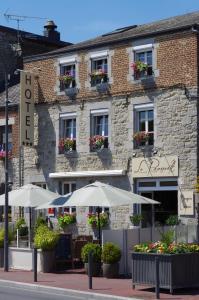 a hotel with tables and umbrellas in front of it at Hôtel Le Roosevelt in Givet