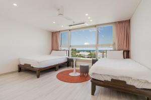 a bedroom with two beds and a table and a window at Jeju Stayra in Sowang-dong