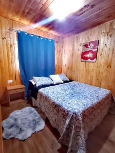 a bedroom with a bed with a blue curtain at cabañas eco chahuilco in Constitución