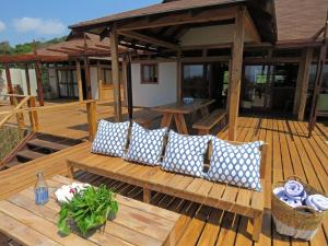 Una terraza de madera con almohadas y un banco encima. en Aloha 16, en Ponta Mamoli