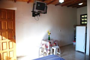 a room with a table and a tv on a wall at Chalés na Mata Ubatuba in Ubatuba