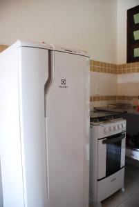 a white refrigerator in a kitchen with a stove at Chalés na Mata Ubatuba in Ubatuba