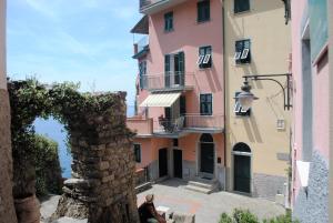a woman sitting on a bench in front of a building at Affittacamere Piazza Castello in Manarola