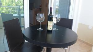 a black table with two glasses and a bottle of wine at Apartment Hotel Prego in Ulcinj