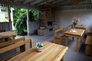 eine Terrasse mit Holztischen und -bänken und einem Kamin in der Unterkunft Marbella in Ventspils