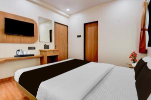 a bedroom with a bed and a tv on the wall at Super Townhouse Balewadi Stadium Pune Formerly Hotel Sarovar in Pune +23 photos