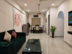 a living room with a green couch and a table at Staeg Nirvana 2BHK in Indore