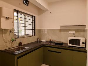a kitchen with a sink and a microwave at Staeg Nirvana 2BHK in Indore